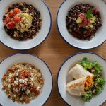 Top view of four healthy grain and vegetable bowls on a wooden table, perfect for nutritious meal ideas.
